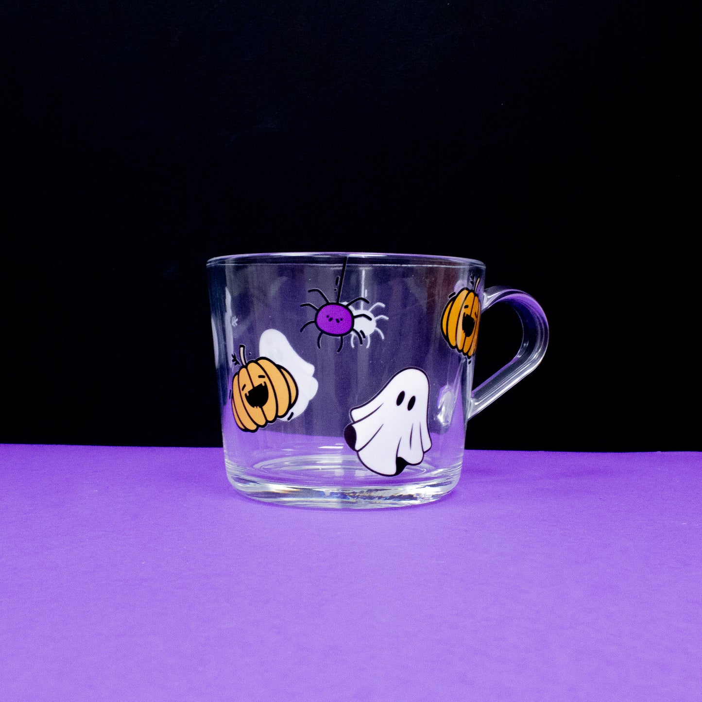 Halloween-themed glass cup featuring playful designs of pumpkins, ghosts, and spiders, perfect for seasonal drinks